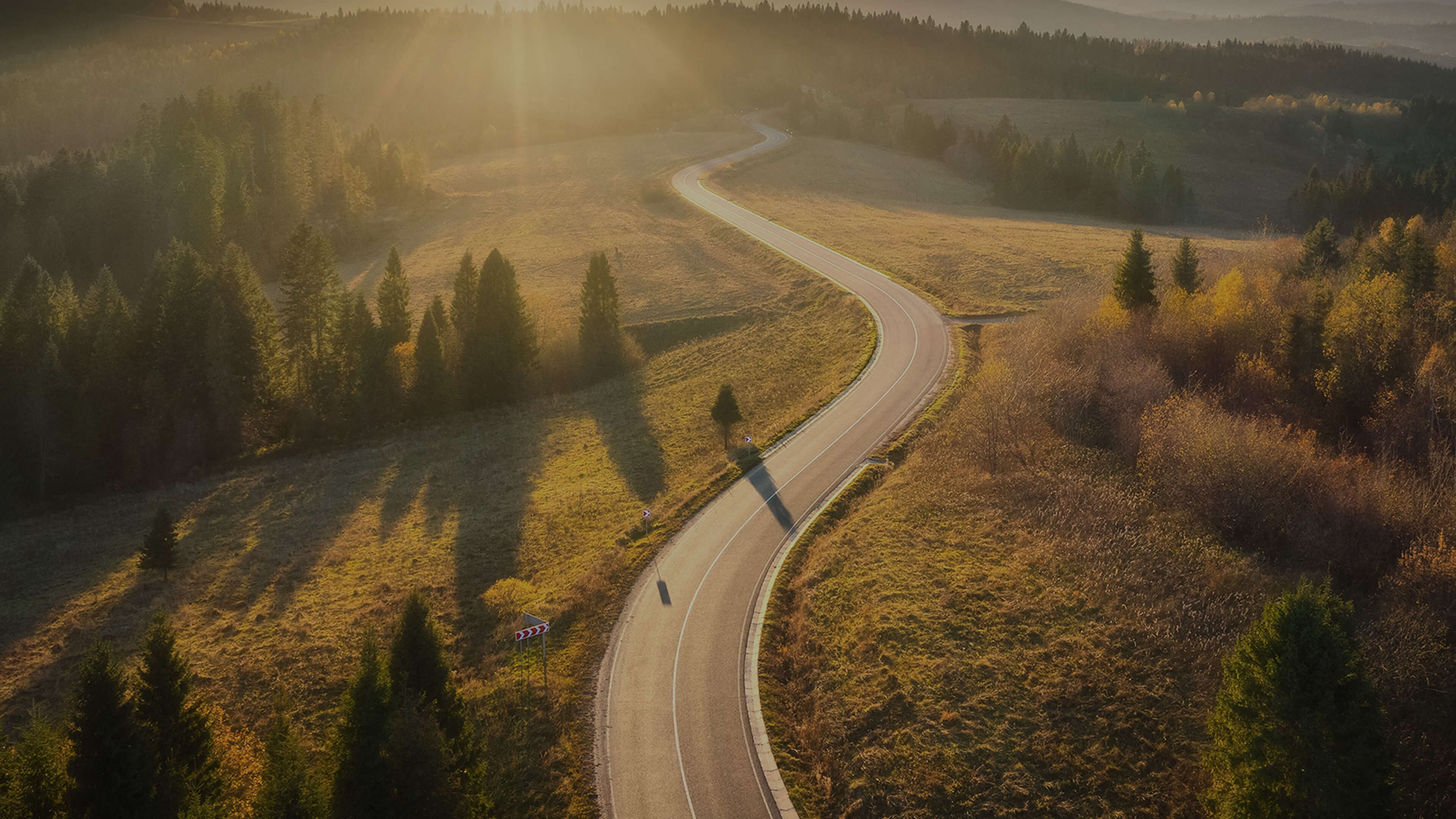 The Kia PBV logo overlaid on an open road through scenic landscape at sunset