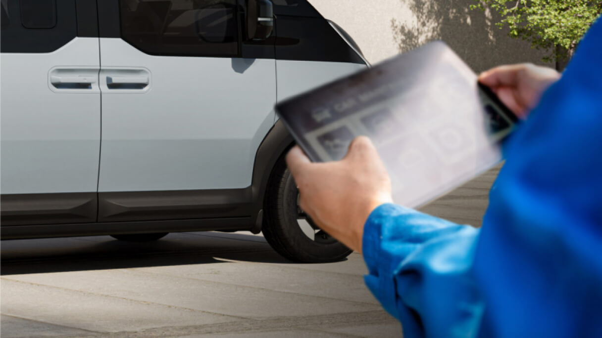 Close-up of hands using a digital device near a vehicle engine, showing real-time access to Kia FMS (Fleet Management Solutions) and Data Services