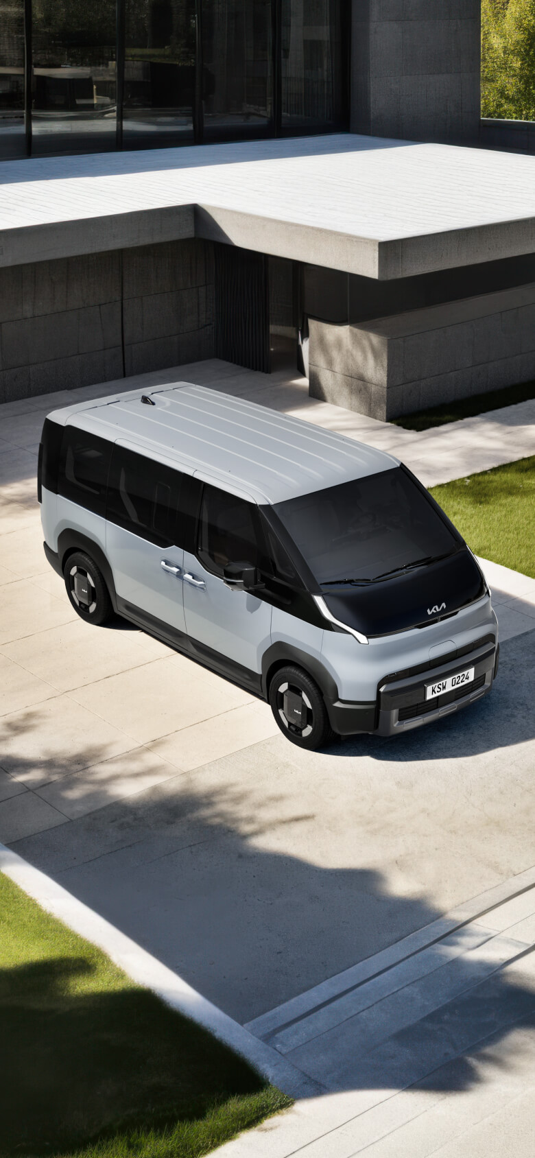 Front-side view of the Kia PV5 Passenger in an outdoor driveway setting