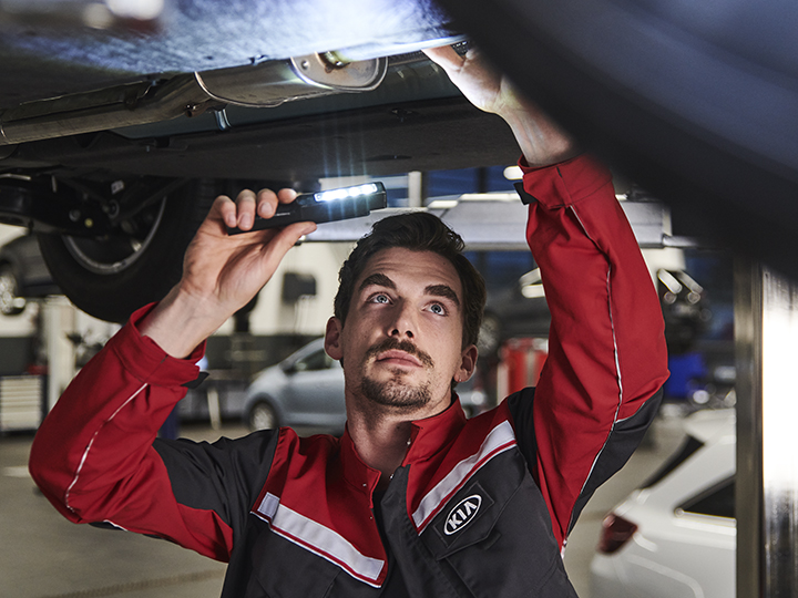 Mechanic repairs something on the engine under the car 