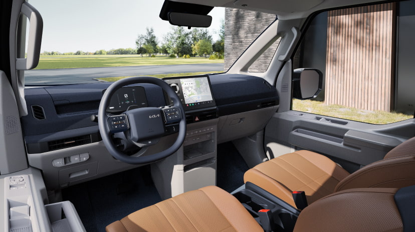 Driver-side interior of the Kia PV5 Passenger with tan seats and digital cockpit display
