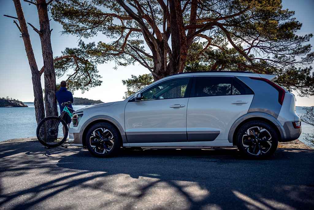 Nya Kia Niro EV står parkerad vid vattnet, i bakgrunden syns en person med en cykel.